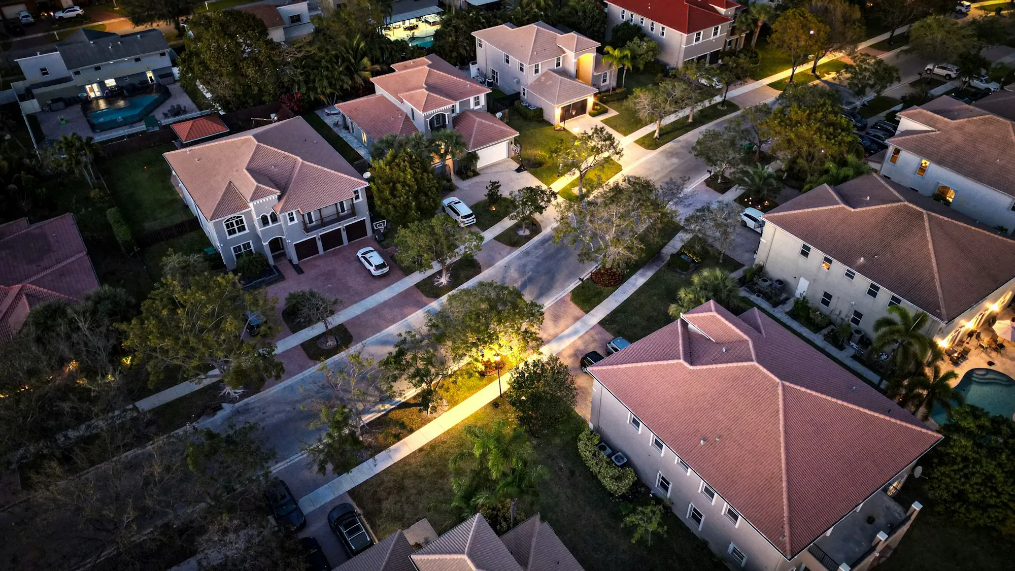 Aerial view of homes and lit streets at dusk